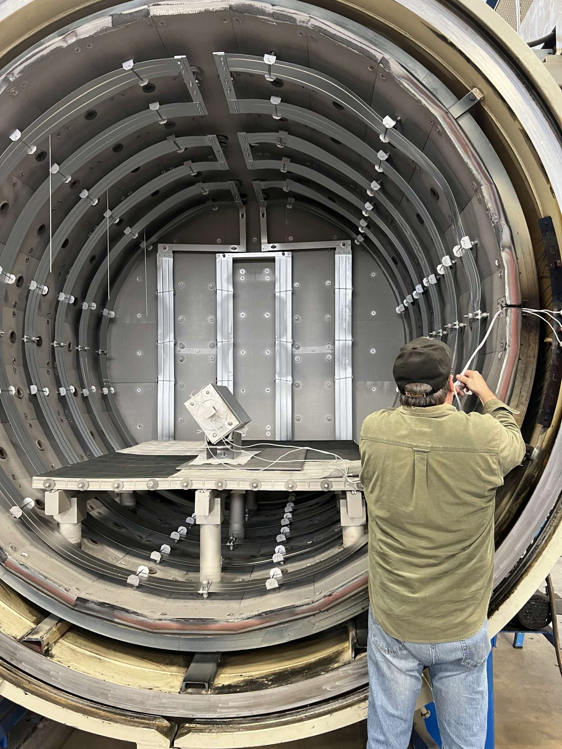 An HTG technician working inside an open vacuum brazing furnace